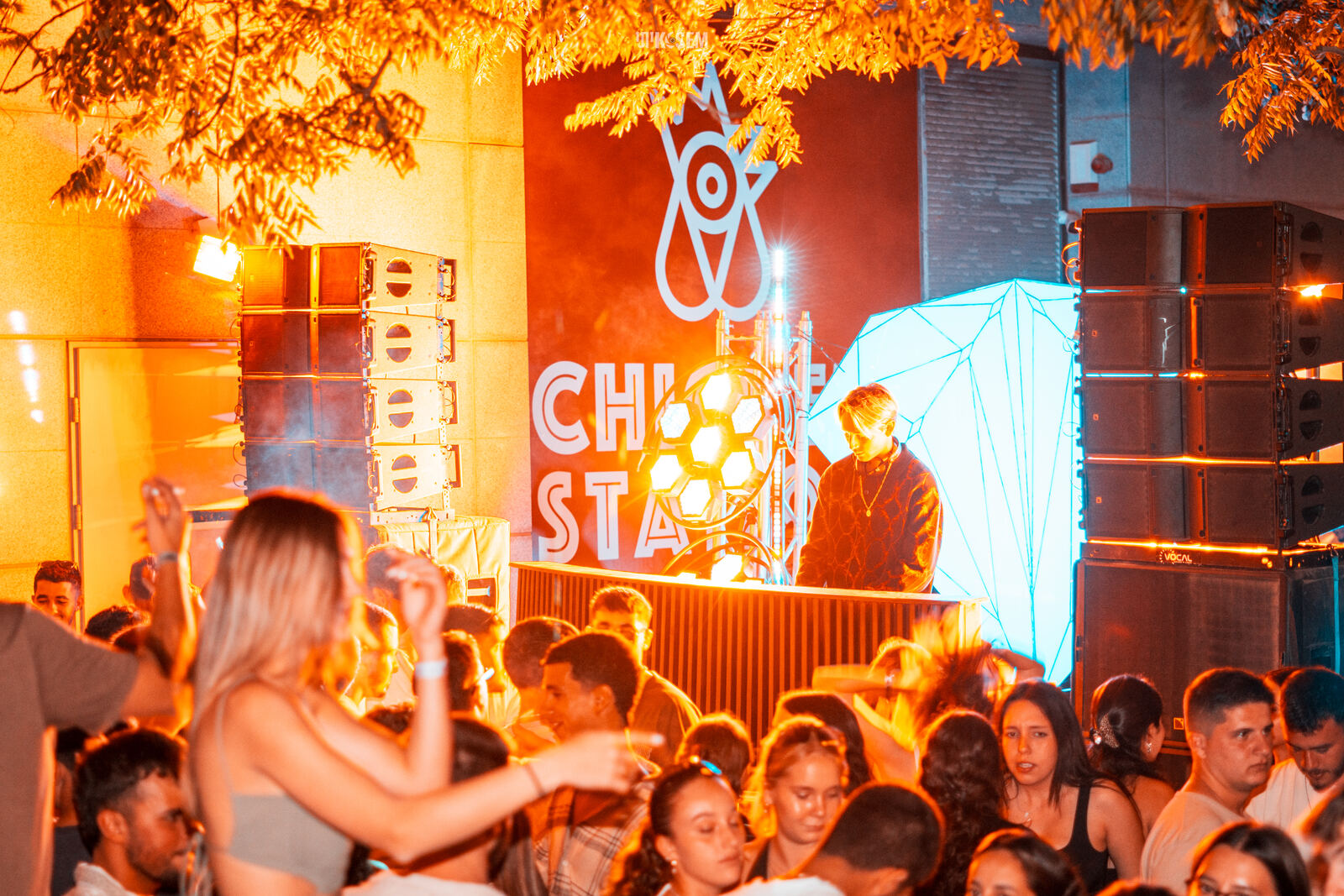 קהל רוקד מול עמדת DJ וקיר רמקולים באירוע סוף מסלול